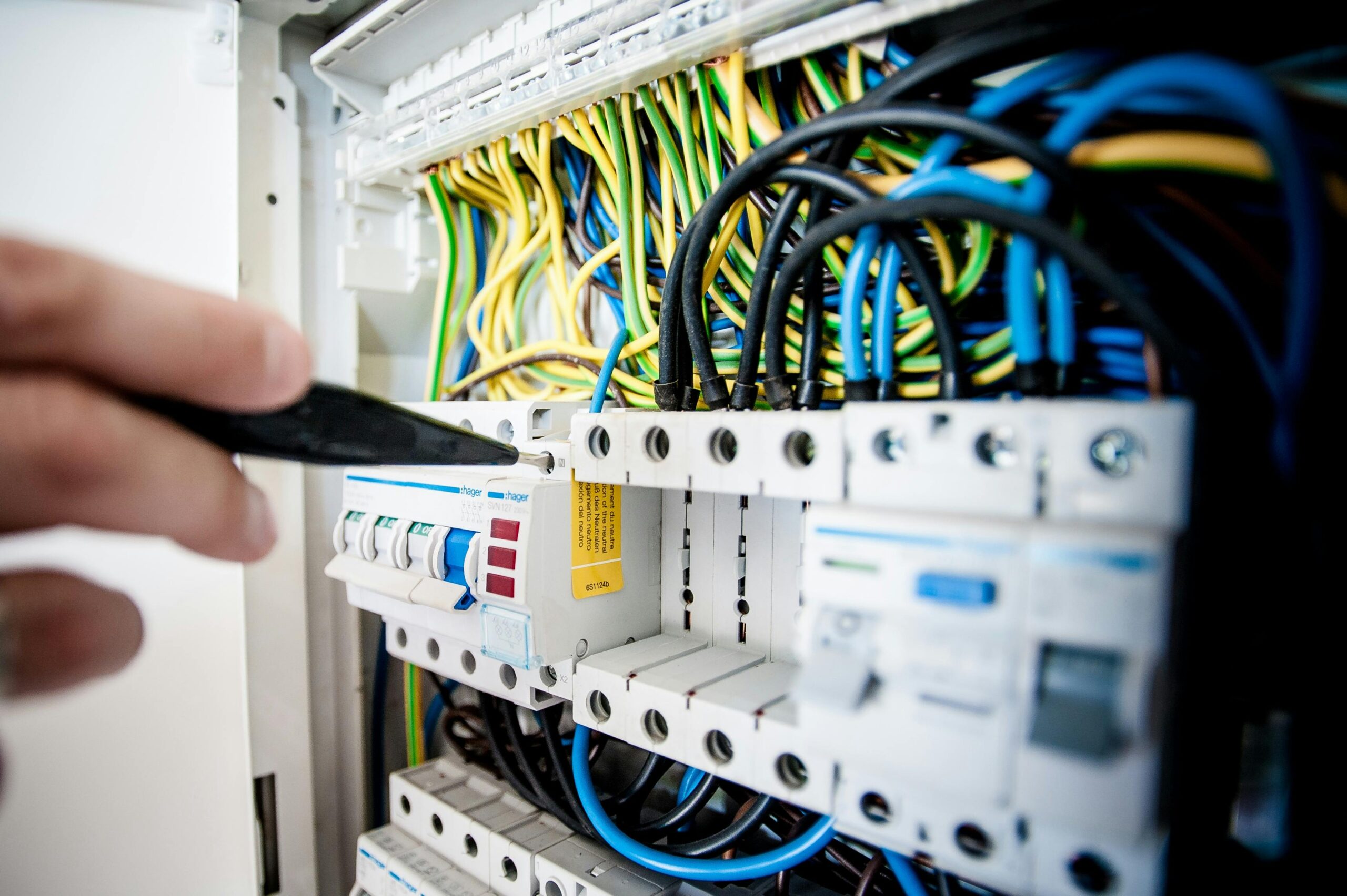 Elektriker arbeitet mit Schraubendreher an Sicherungen in einem Schaltschrank